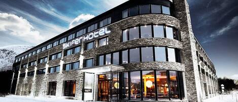 A modern hotel with a curved facade, large windows, and a stone exterior.