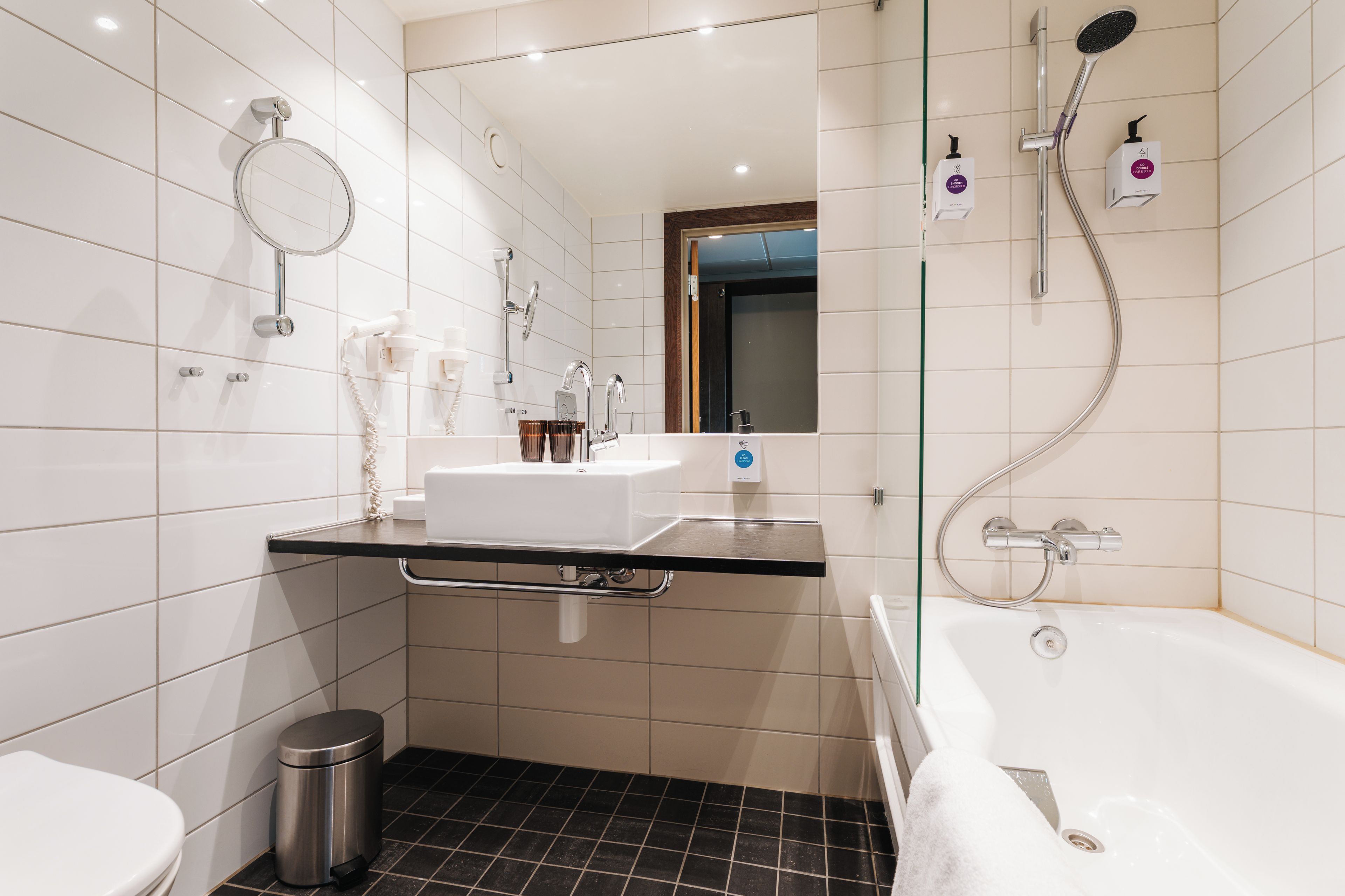 Une salle de bain moderne avec une douche à parois de verre, un lavabo blanc et des toilettes séparées.