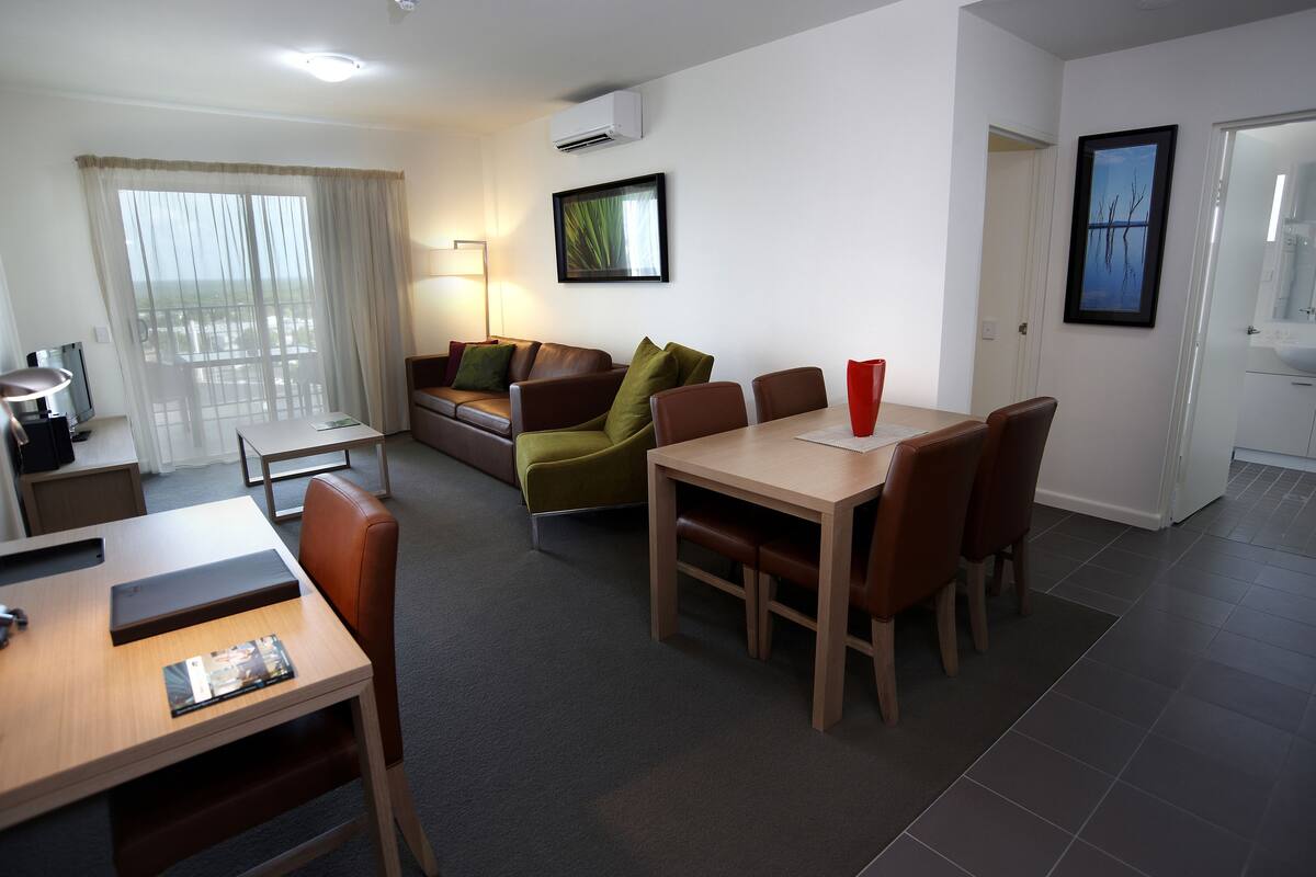 Una sala de estar moderna con comedor, sofá, mesa de centro y televisor.