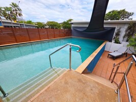 Una piscina al aire libre, sillones reclinables de piscina