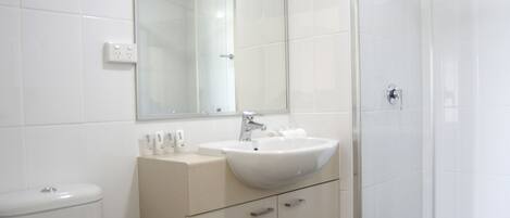 Un baño con inodoro, lavamanos, espejo y ducha.