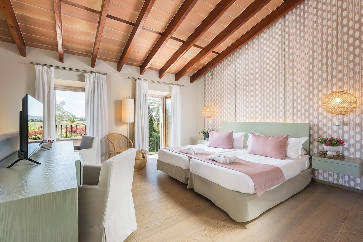 Un dormitorio con cama, mesitas de noche, una silla, escritorio y televisor.
