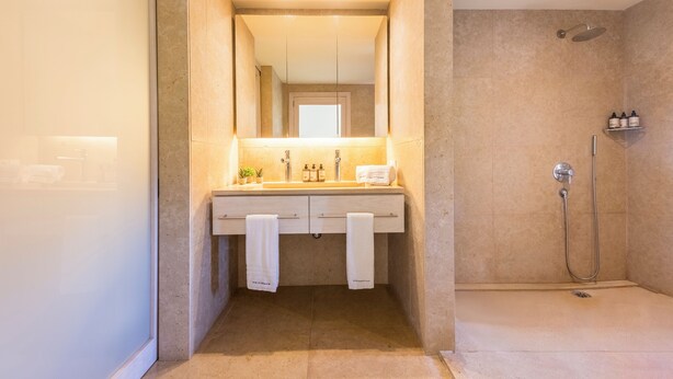 Een badkamer met een wastafel, spiegel en douche.