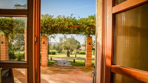 Una entrada abierta que da a un jardín con una pérgola, pilares de ladrillo y un sendero de piedra.