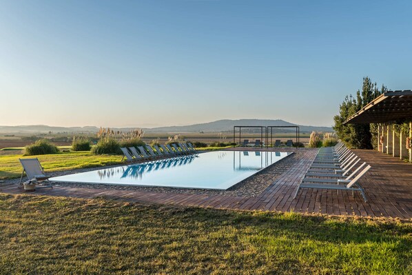 Una piscina al aire libre, sombrillas, tumbonas