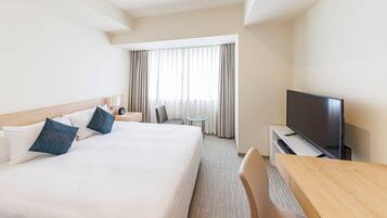 A hotel room with a large bed, a TV, a desk, and a chair.