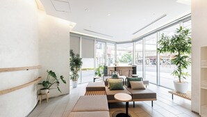 A modern interior with seating areas, potted plants, and large windows offering views of the street. - Fraser Residence Nankai Osaka (Osaka)