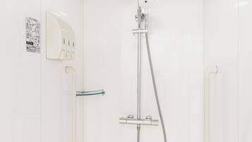 Un baño pequeño y blanco con ducha, un perchero para toallas y un dispensador de jabón de pared.