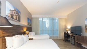 Een hotelkamer met twee bedden, een bureau met televisie en een groot raam met gordijnen.