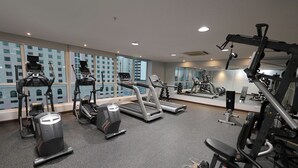 Een fitnessruimte met loopbanden, elliptische trainers en gewichten.