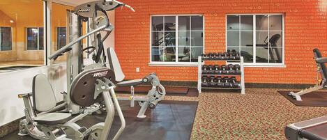 Un gimnasio con equipamiento de ejercicio, un espejo y una ventana con vistas.