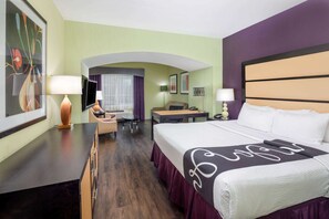 Una habitación de hotel con una cama grande, un escritorio, una silla, un televisor y un sofá.