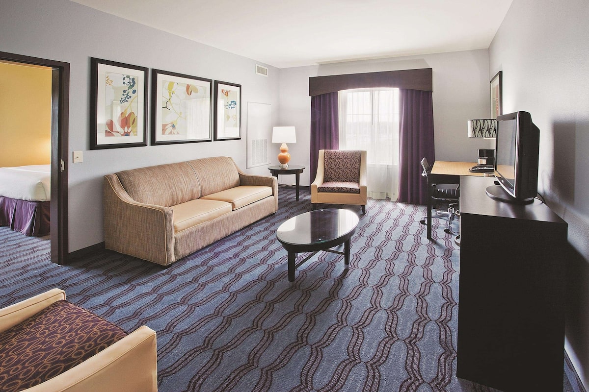 Ein Hotelzimmer mit Sofa, Sessel, Schreibtisch und Fernseher.