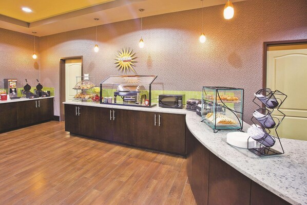 Un área de cocina moderna con barra americana, estación de café y microondas.