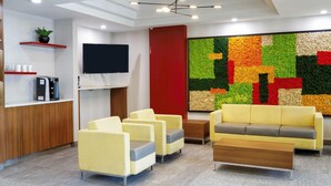Una zona de recepción moderna con un televisor de pantalla plana, una puerta roja e instalación artística de colores en la pared.