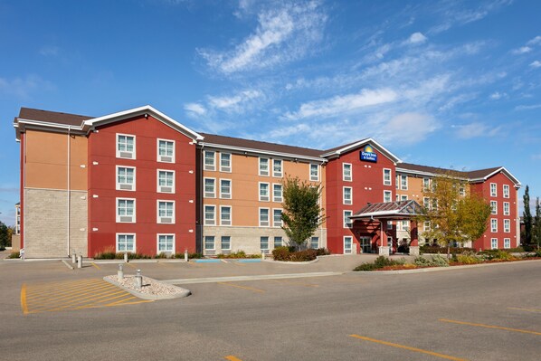 Un hôtel à plusieurs étages, avec une façade rouge, une entrée centrale et un parking.