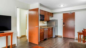 A compact kitchen with wooden cabinets, a microwave, a refrigerator, and a dishwasher.