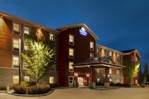 Un hôtel à plusieurs étages, reconnaissable à son grand panneau « Days Inn & Suites », doté d’une entrée couverte et d’un parterre aménagé devant l’établissement.