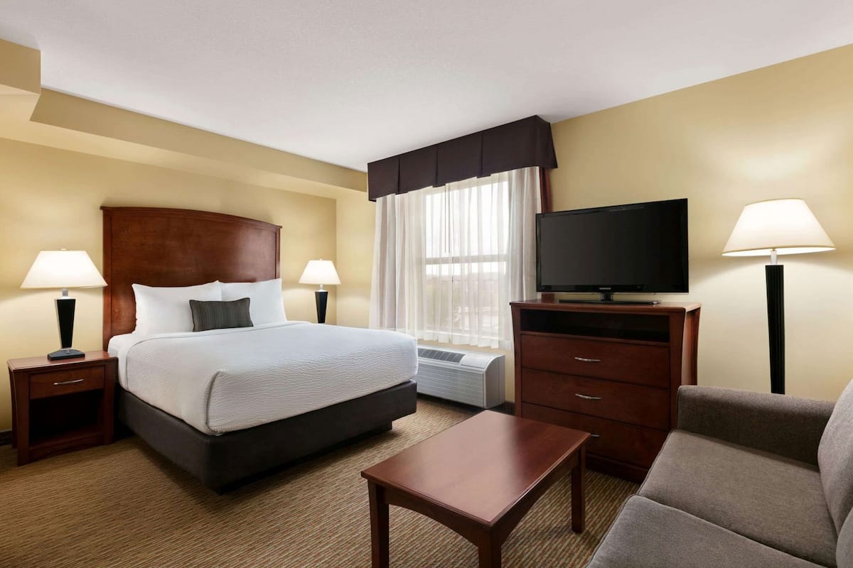 Una habitación de hotel con cama, televisión, escritorio, silla y lámpara.