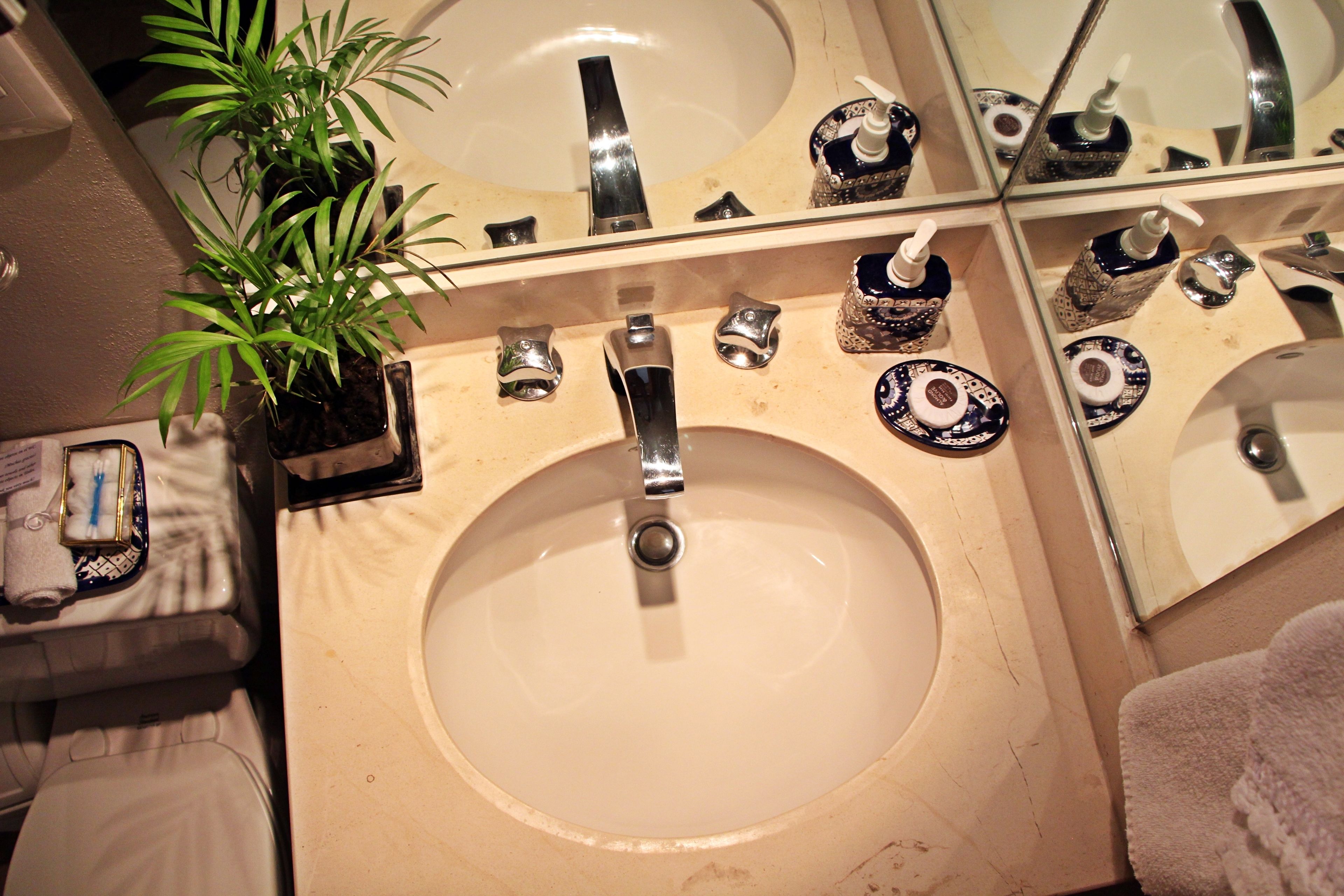 A bathroom with a sink, mirror, and toiletries.
