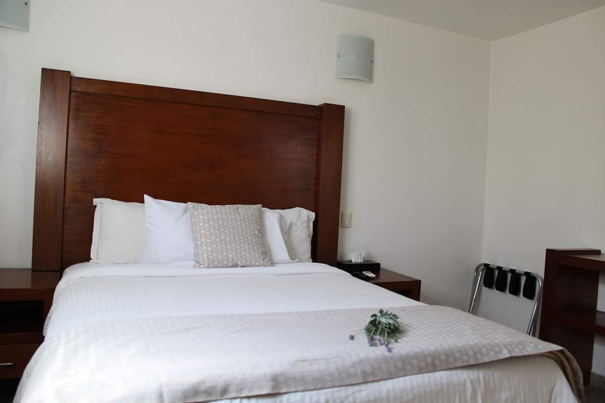 A neatly made bed with a wooden headboard, white bedding, and a small decorative plant on the bed.