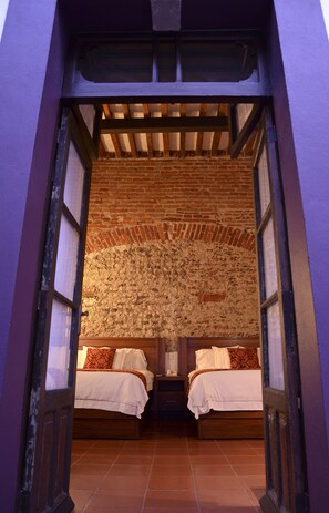 A room with two beds, a brick wall, and a wooden ceiling. - El Serafin Hotel Boutique (Querétaro)