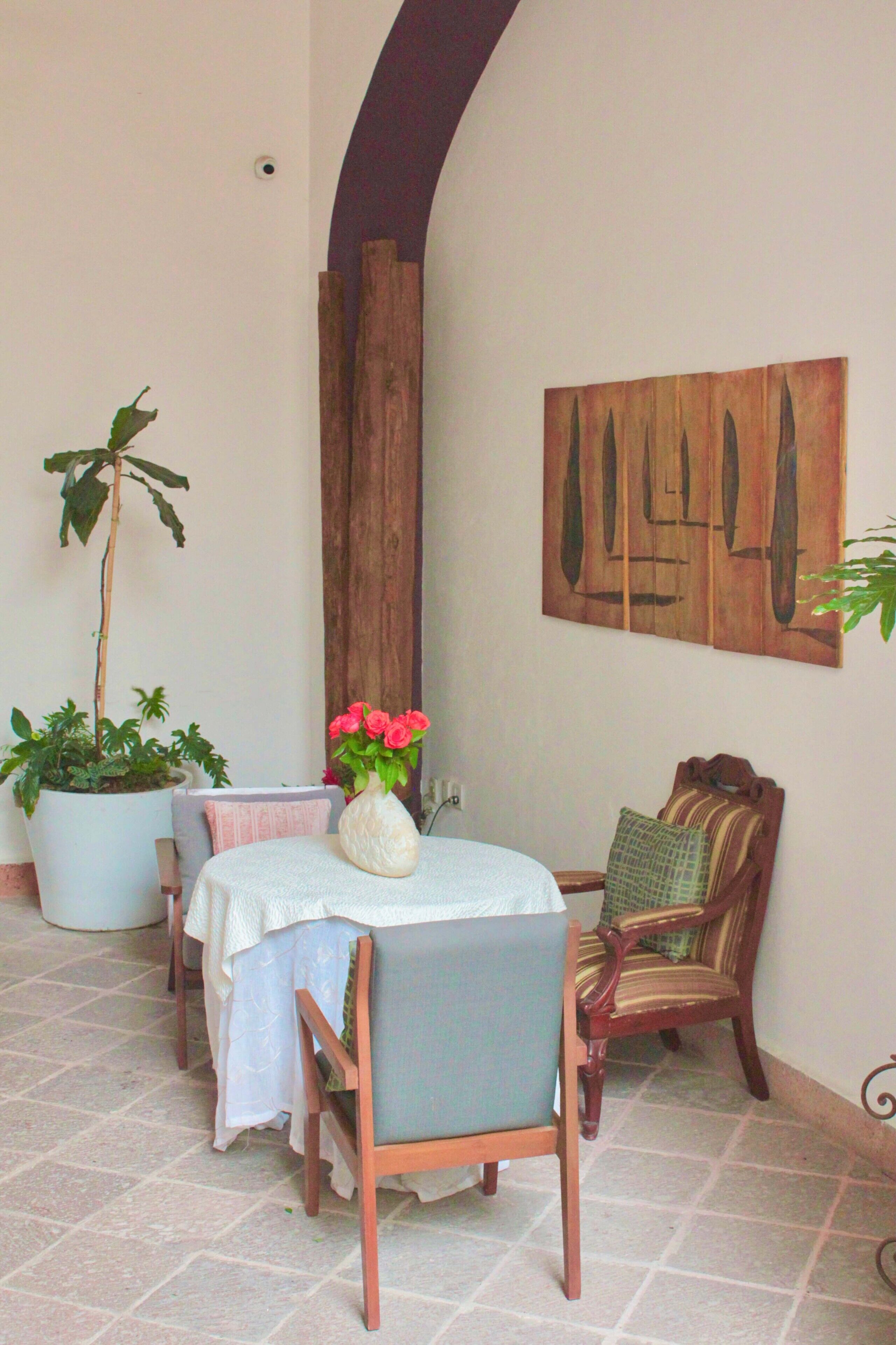 A dining area with a table, chairs, a potted plant, and a wall-mounted artwork.