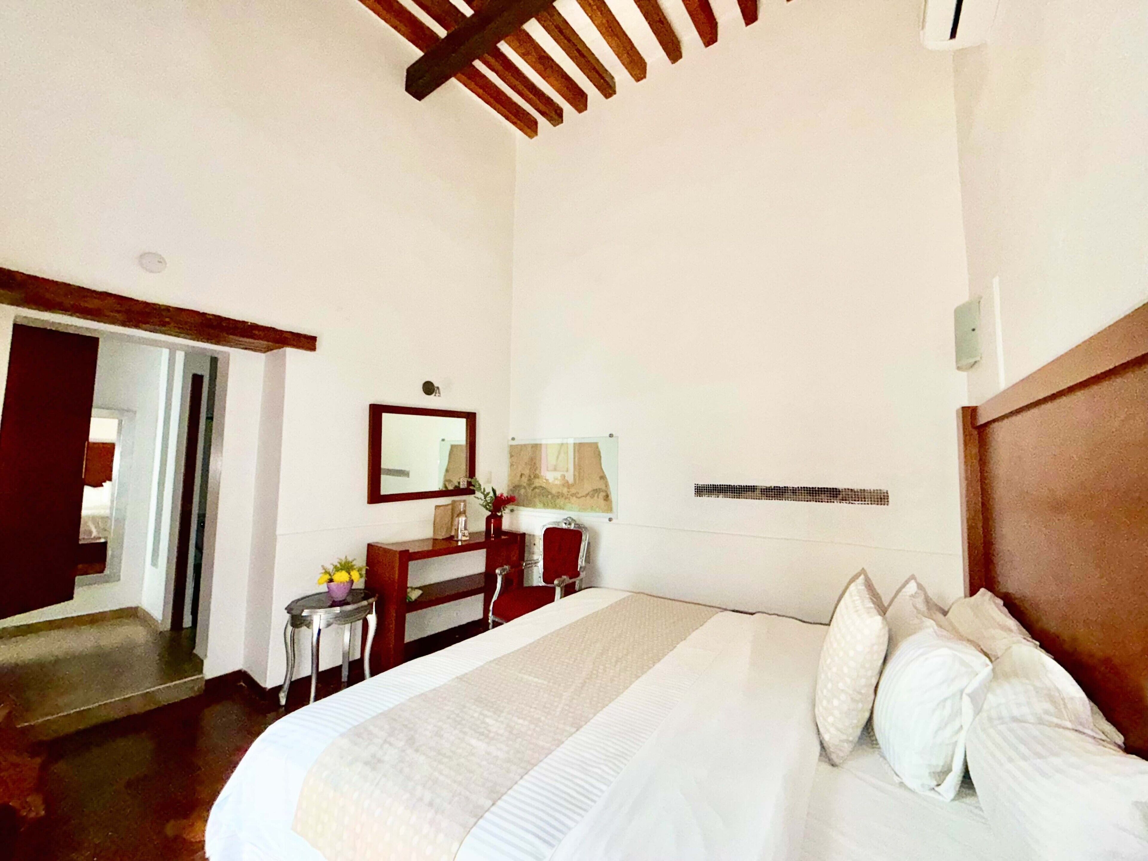 Una habitación de hotel con una cama grande, un escritorio, una silla y un espejo.