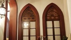 Una habitación con dos puertas de madera arqueadas, un sofá tejido y un piso de baldosas.