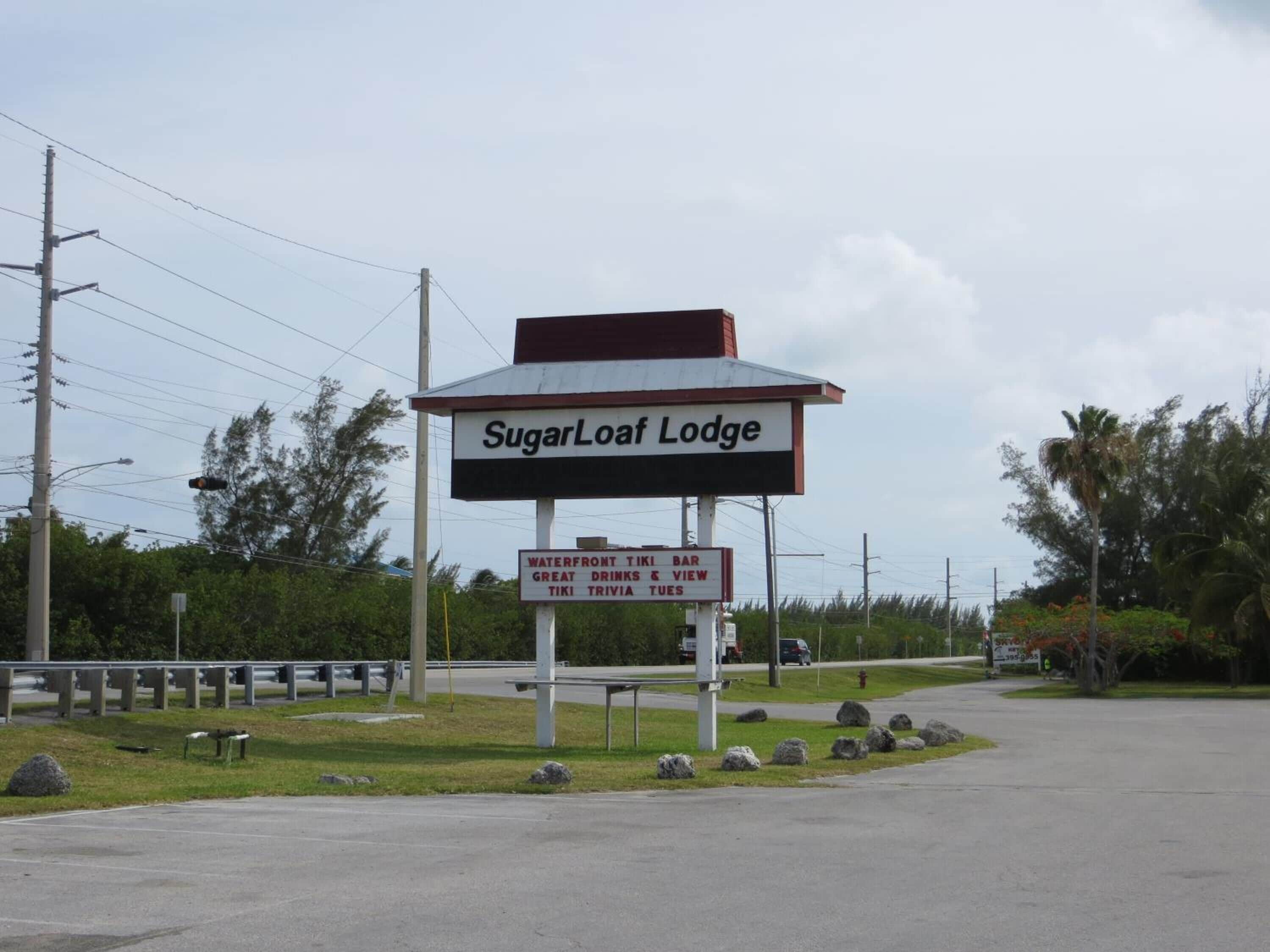 A sign for SugarLoaf Lodge advertising waterfront tiki bar, great drinks, and trivia nights.