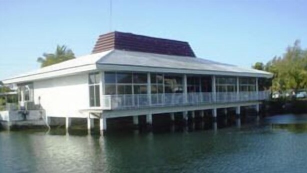 Un immeuble situé au bord de l’eau, doté d’un toit plat, de grandes fenêtres et d’un balcon.