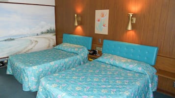 Une chambre d’hôtel avec deux lits, des panneaux de bois au mur, un tableau représentant une plage et des lampes fixées au mur.