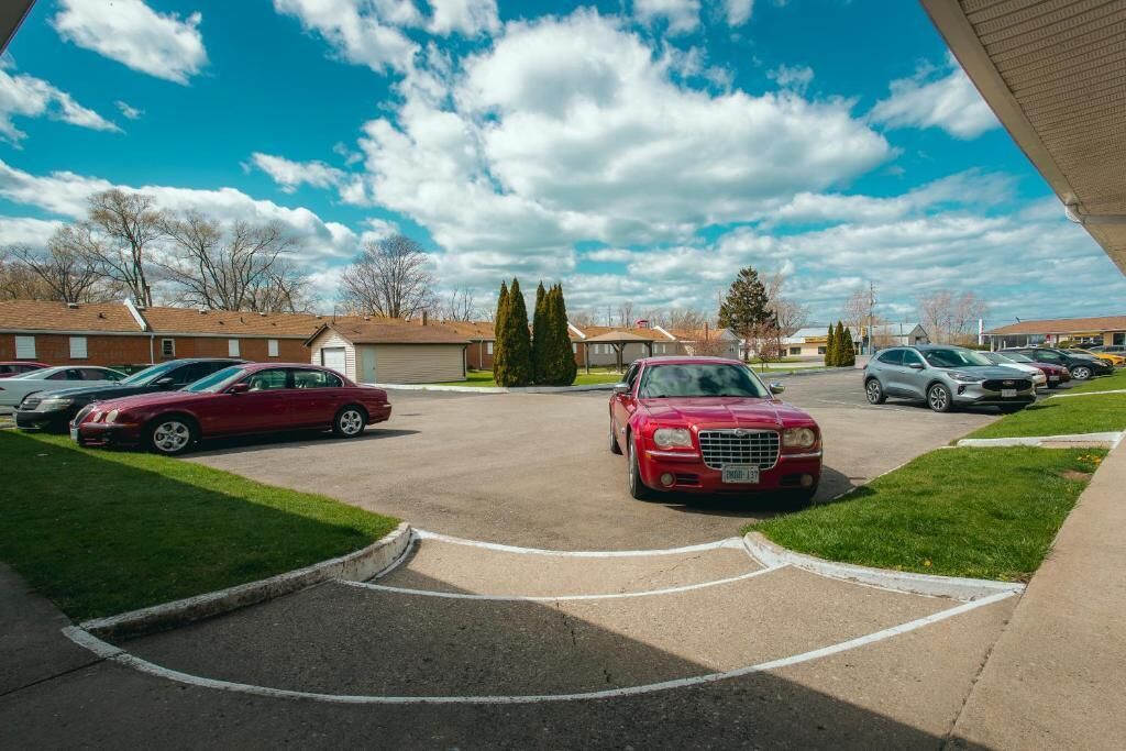 A parking lot with cars, a building with a sloped roof, and a clear sky.
