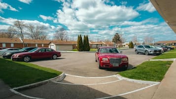 A parking lot with cars, a building with a sloped roof, and a clear sky.