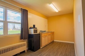 A compact kitchen with a microwave, refrigerator, and wooden cabinets. - Fauld's Motel (Sarnia)