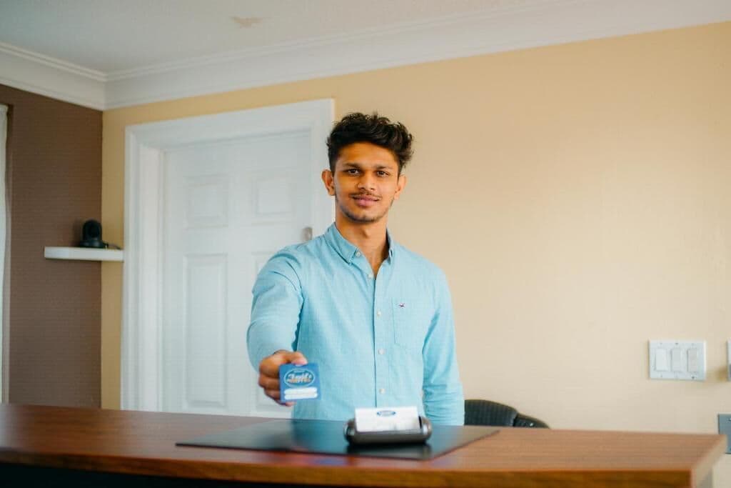 A person standing at a wooden table with a card and a card reader.