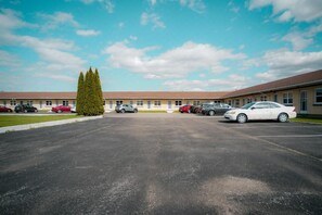 Un estacionamiento con varios coches, un edificio de techo plano y cielo despejado.