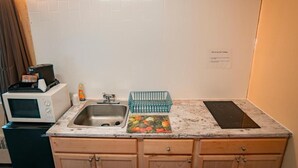 Cocina compacta con microondas, lavamanos y una pequeña encimera.