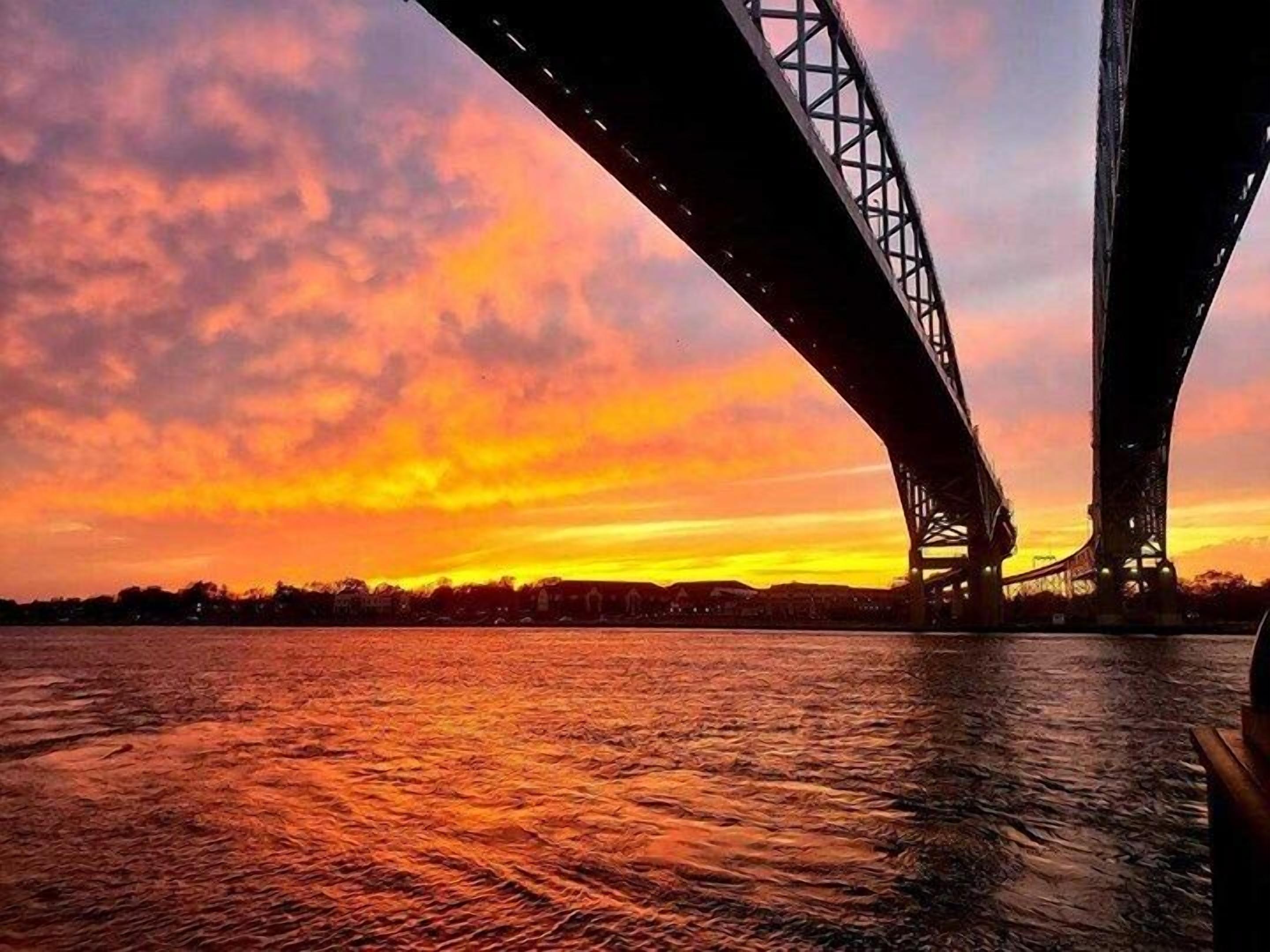 A bridge with two large spans over a body of water during sunset.