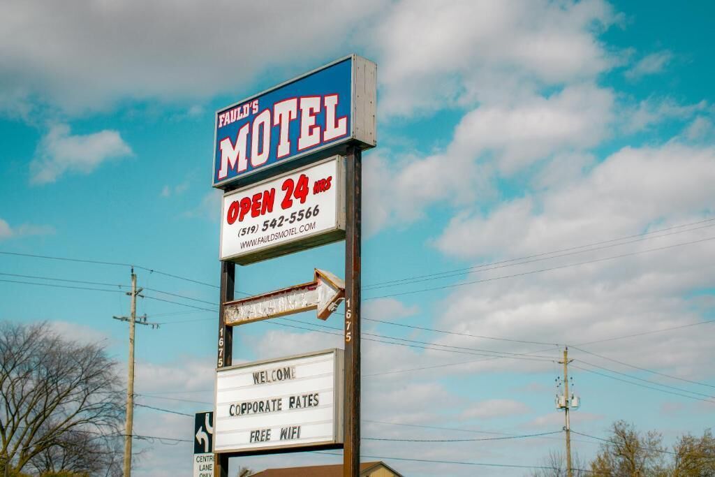A motel sign with 'FAUL'S MOTEL' and 'OPEN 24 HOURS' prominently displayed.