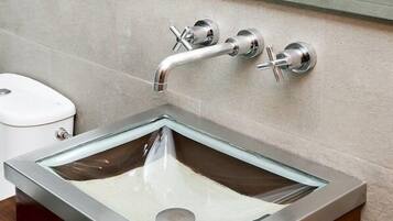 Une salle de bain moderne avec un lavabo en verre, un robinet chromé et des toilettes.
