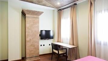 A room with a bed, a desk, a chair, a television, and a large window with curtains.