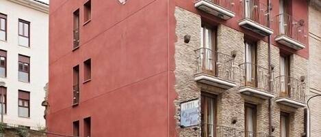 Un edificio de varios pisos con fachada roja, numerosas ventanas y balcones.