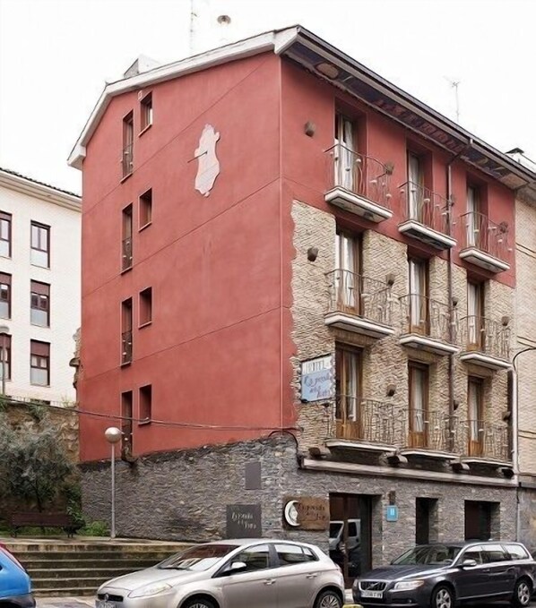 A multi-story building with a red facade, multiple windows, and balconies.