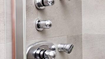 A bathroom with a modern shower system, including a control panel and multiple shower heads.