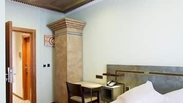 A hotel room with a bed, a desk, a chair, and a small table with a telephone.