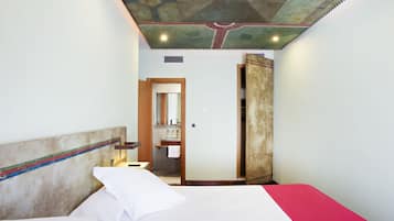 Una habitación de hotel con cama, baño y puerta que da a otra habitación.