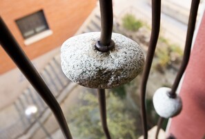 A close-up of a stone balustrade with a metal post, part of a building's exterior.