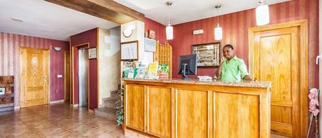 Zona de recepción con mostrador de madera, una recepcionista y un escritorio.