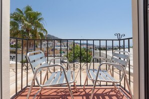 A balcony with two metal chairs and a view of a coastal town. - Hotel Al Andalus (Nerja)